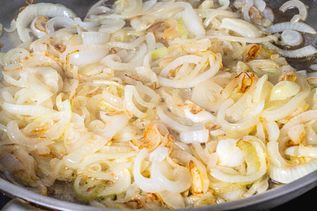 The onion is fried in a pan. The process of cooking onion soup. Caramelization of onions. High quality photoの写真素材