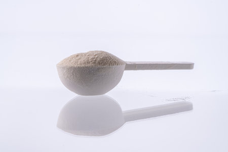 Collagen powder in a measuring spoon on a white background with reflection. A dietary supplement for beauty, health and weight loss. High quality photoの写真素材