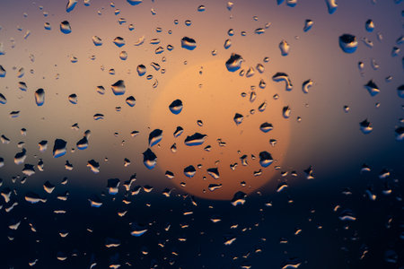 Raindrops on the window against the background of the setting sun. Background with glass and drip texture. High quality photoの写真素材