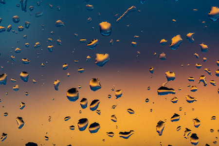 Raindrops on the window against the background of the setting sun. Background with glass and drip texture. High quality photoの写真素材