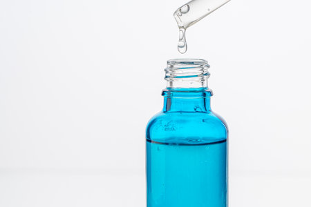 Dropper with a drop of hyaluronic acid and collagen serum and a blue bottle on a white background. Close-up. Copyspace. High quality photoの写真素材