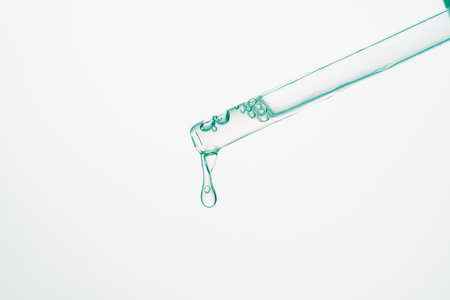 Pipette with a drop of serum or medicine on a white background. Collagen or hyaluronic acid for facial skin care. Copyspace. Close-up. High quality photoの写真素材