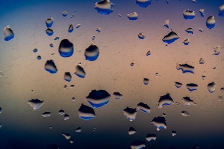 Raindrops on the window against the background of the setting sun. Background with glass and drip texture. High quality photoの写真素材
