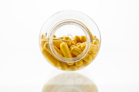 A jar with pills inside lies on a white background. Hyaluronic acid, collagen, vitamins or barberry for weight loss. Medicine for health and beauty. Copyspace, close-up. High quality photoの写真素材