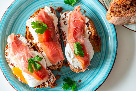 Toast with poached egg, cream cheese and red fish on a blue plate. Delicious and healthy breakfast. Top view. High quality photoの写真素材