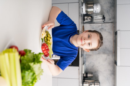 Beautiful little girl sitting at table with plate of spinach waffles and cherry tomatoes. The concept of a delicious and healthy breakfast. Selected focus. High quality photoの写真素材