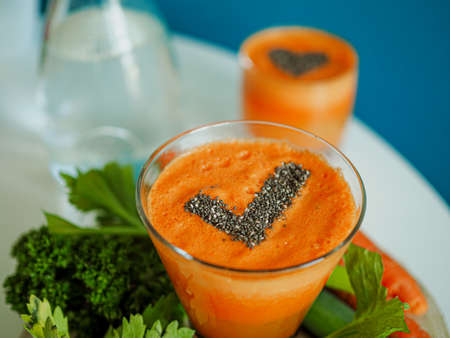 bird view of a glass with healthy cold pressed carrot apple juice and chiaseeds on top in the form...