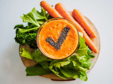 bird view of a glass with healthy cold pressed carrot apple juice and chiaseeds on top in the form of a checkmark for a successfully completed juicing detox fastの写真素材