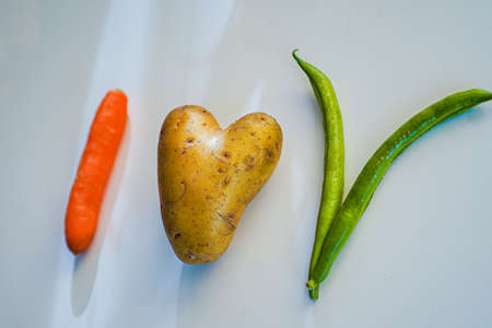 Top view of â€œI love vegan veggie organic food letters with a heart shaped raw potato
