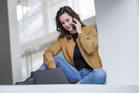 smiling easy going remote working lady girl calling and chatting in front of a laptop or notebook in...