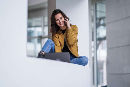 smiling easy going remote working lady girl calling and chatting in front of a laptop or notebook in...