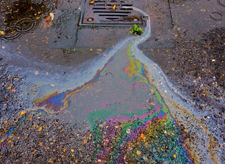 Petrol Oil on a Road Running Down a Gutter Drainの写真素材