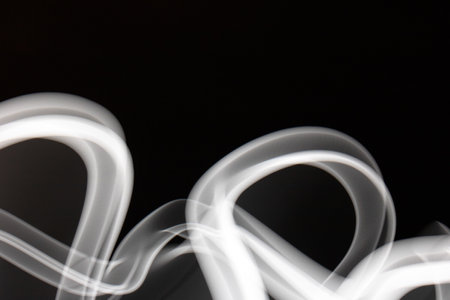 A Swirling White Smoke Light on a Black Backgroundの写真素材