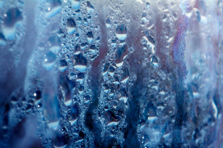 Deilcate Rain Drops of Water on Glass in a Blue Glow for Background