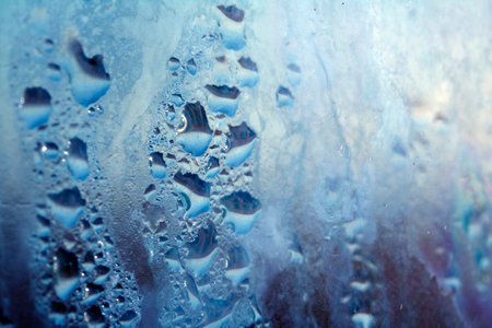 Delicate Rain Drops of Water on Glass in a Blue Glowの写真素材