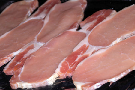 CLose Up of Raw Uncooked Bacon Slices Ready to be Cooked