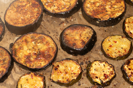 A roasted sliced seasoned aubergine eggplant courgette with salt and herbs cooked in the oven close upの写真素材