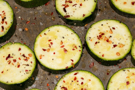 A seasoned sliced courgette with salt and herbs waiting to be cooked in the oven close up rawの写真素材
