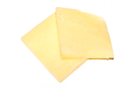 Close up of chedder cheese slices on a white backgroundの写真素材