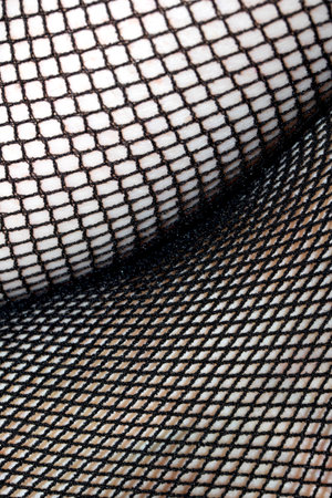 Close up of black fishnet tights on skin legs curves abstract backgroundの写真素材