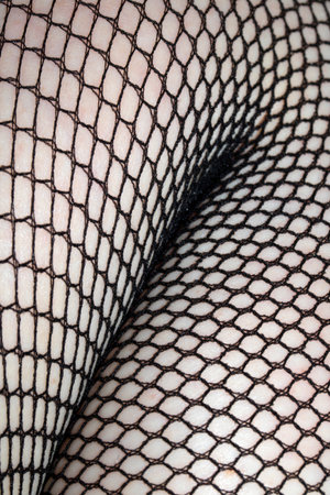Close up of black fishnet tights on skin legs curves abstract backgroundの写真素材