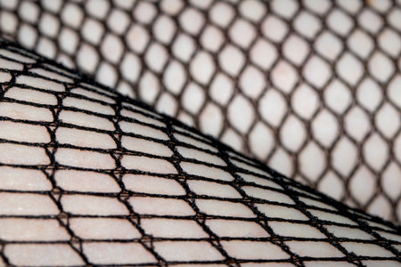 Close up of black fishnet tights on skin legs curves abstract backgroundの写真素材