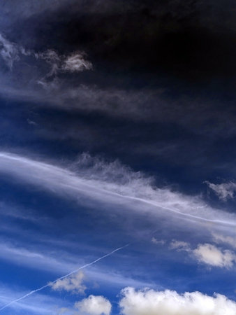 Close up of atmospheric blue black sky with whispy white clouds