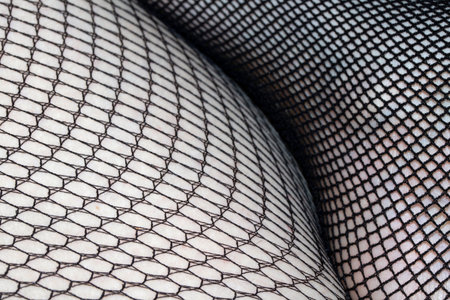 Close up of black fishnet tights on skin legs curves abstract backgroundの写真素材