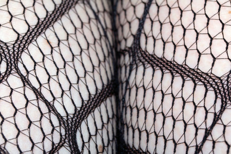Close up of black fishnet tights on skin legs curves abstract backgroundの写真素材