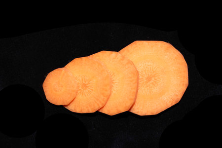 Chopped Sliced Orange Carrot Vegetable Pieces on Black Backgroundの写真素材