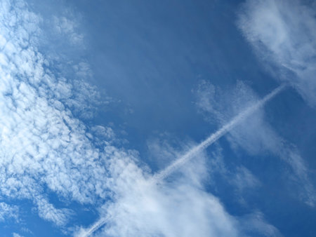 Blue Skies with wispy chemtrail aeroplane lines and fluffy white clouds