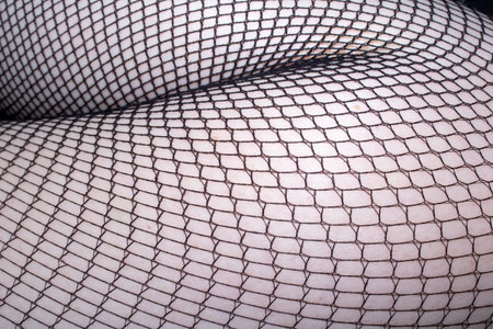 Close up of black fishnet tights on skin feet legs curves abstract backgroundの写真素材
