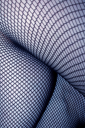 Close up of black fishnet tights on skin feet legs curves abstract backgroundの写真素材