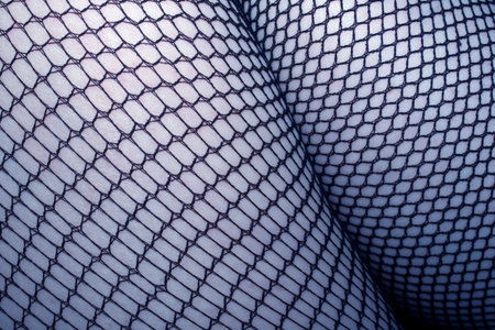 Close up of black fishnet tights on skin feet legs curves abstract backgroundの写真素材