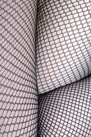 Close up of black fishnet tights on skin feet legs curves abstract background