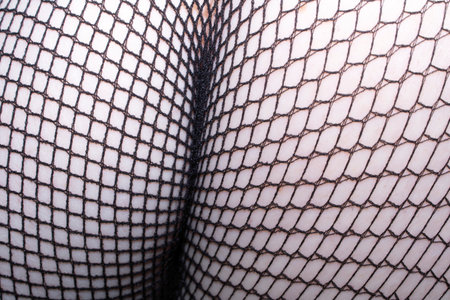 Close up of black fishnet tights on skin feet legs curves abstract backgroundの写真素材