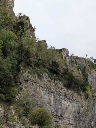 Tall cliff face jagged rocks and stone gorge mountins with clear sky in the UK landscape
