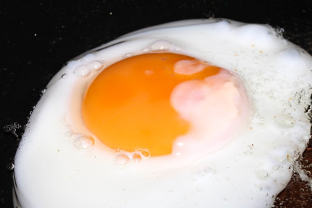 Close up of Fresh egg frying in a pan with golden yolkの写真素材