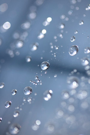 Close up of abstract floating bubbles water droplets condensation rain on a glass transparent bokeh backgroundの写真素材