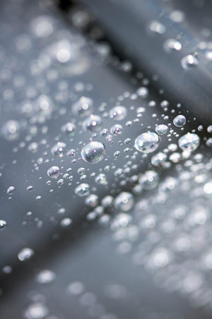 Close up of abstract floating bubbles water droplets condensation rain on a glass transparent bokeh backgroundの写真素材