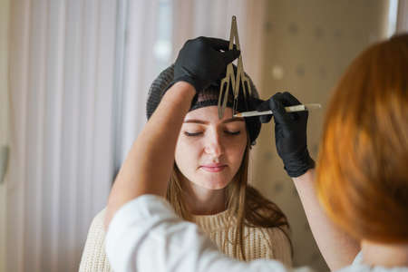 Permanent, Girl-master beautician makes eyebrow tattoo, women during permanent makeup, Permanent eye makeup, Beautician applies eye tattoo, Permanent procedure, Eyebrow correction procedure with permanent makeup, beauty salon, beautician's hands make eyebrow tattoo, permanent eyebrow makeup in a beauty salon , Cosmetology, Master beauticianの写真素材