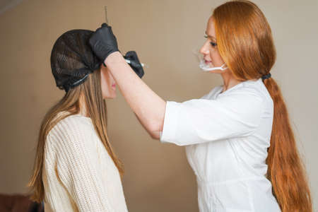 Girl-master beautician makes eyebrow tattoo, women during permanent makeup, Permanent eye makeup, Beautician applies eye tattoo, Permanent procedure, Eyebrow correction procedure with permanent makeupの写真素材