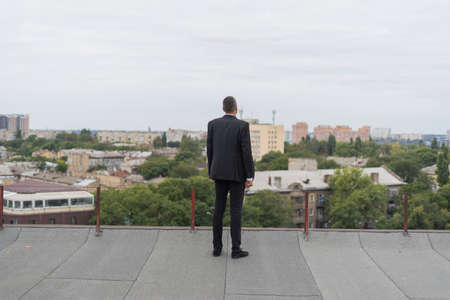 Businessman standing on a roof and looking at city