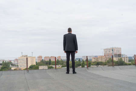 Businessman standing on a roof and looking at cityの写真素材