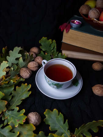 Tea on the background of books, nuts and leavesの写真素材