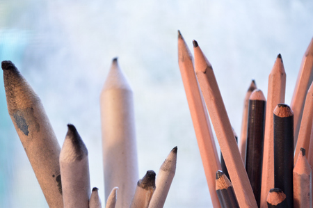 Drawing and sketching tools. Graphite and charcoal pencils for fine art on the right and blending stumps or tortillons for blending pencil drawings to the left. Against a gray and white background. Fine art supplies photographed on site in an artist's stuの写真素材