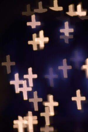Bokeh or defocused image of lights shaped like little crosses in a descending arrangement.の写真素材