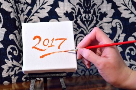 Hand painting the year 2017 on a canvas on easel. New Year's image.の写真素材