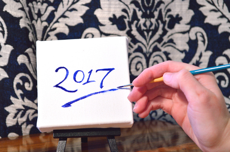 Hand painting the year 2017 on a canvas on easel. New Year's image.の写真素材