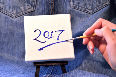 Hand painting the year 2017 on a canvas on easel. New Year's image.の写真素材
